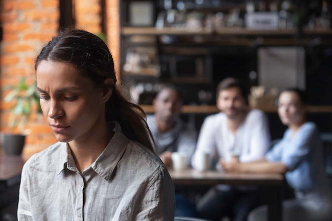 A group of diverse employees avoiding a coworker in a coffee shop after she has been laid off