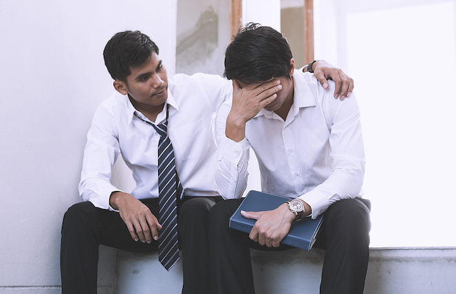 One coworker with his arm around a longtime friend and coworker just being present with him in the office