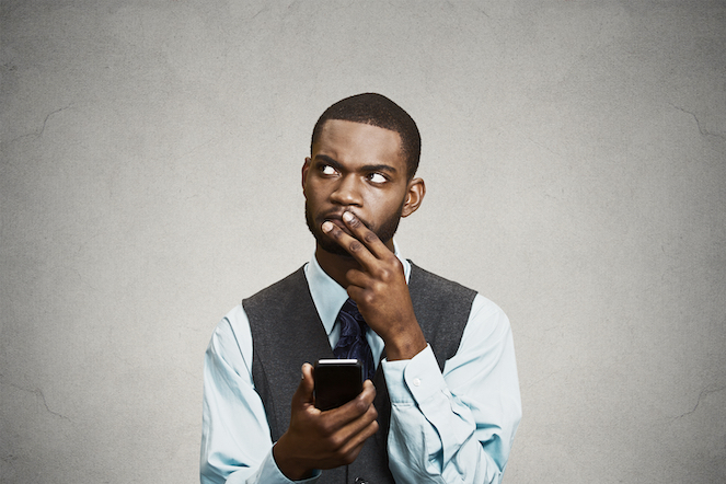 Perplexed and confused man wearing a suit and holding a phone, trying to figure out a solution