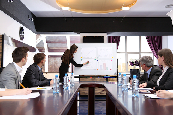 Business training where one colleague is at the front drawing on the board