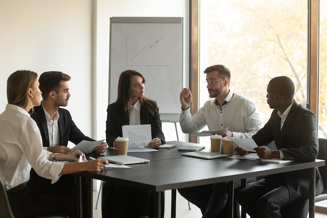 Boss intently listening to her team so they feel seen and heard while discussing company growth.