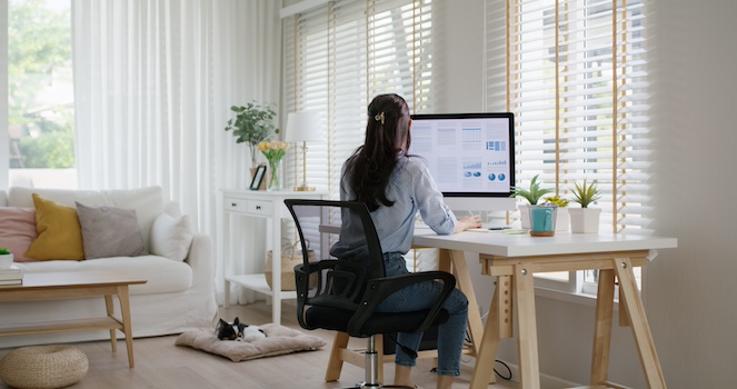 Gen Z remote worker set up in home office with computer and desk facing window in her home.