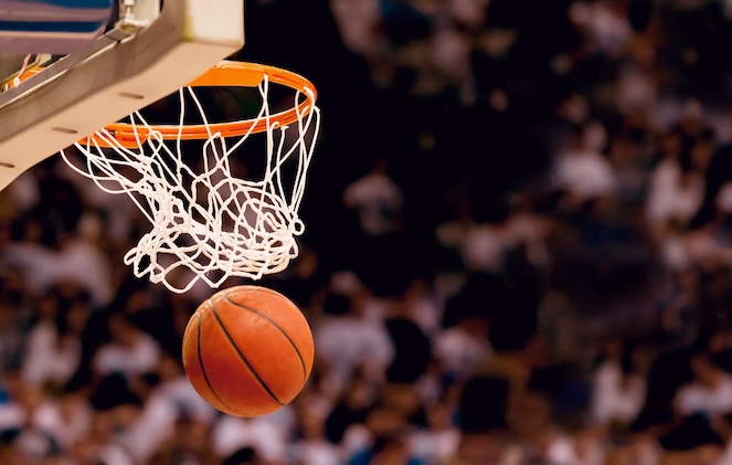 Basketball going through the net with the crowd behind the shot.