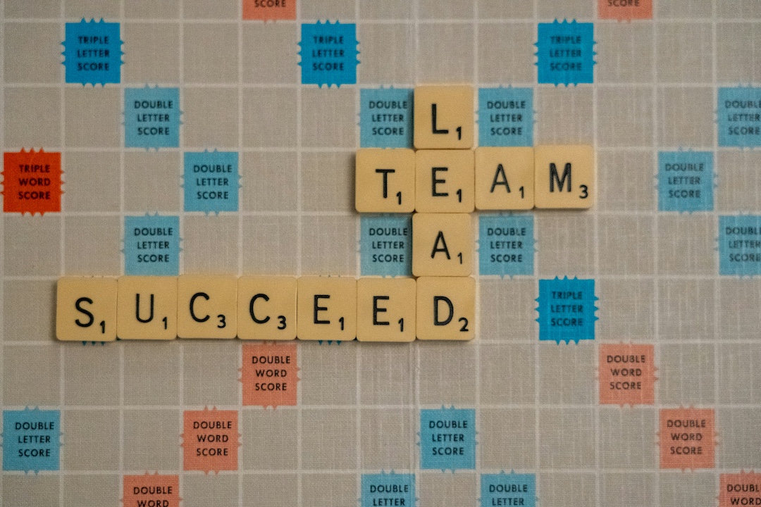 Scrabble board with the words lead, team, and succeed laid out on the board. 