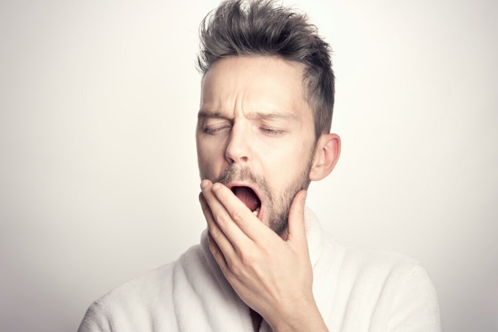 Young man covering his mouth while yawning