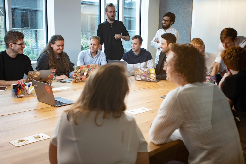 A diverse team sitting around a conference table being productive and lead by a strong leader. This shows a productive team.