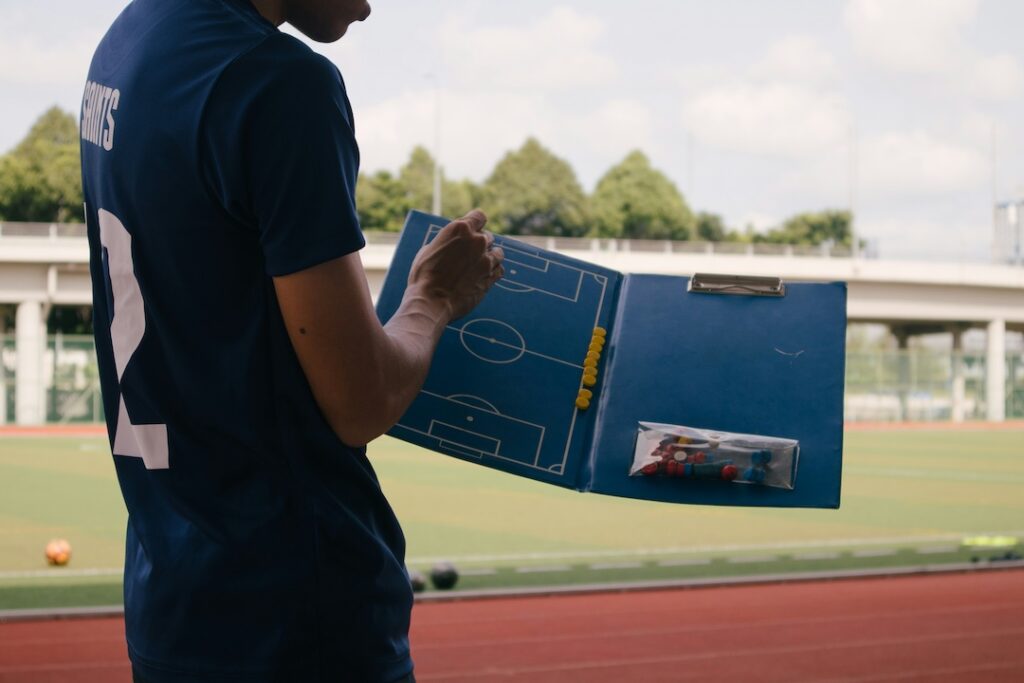 Soccer coach holding open a clipboard and using magnetic pieces to demonstrate a point. 
