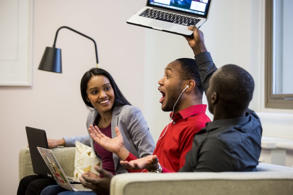 A team on a couch excited about something on the laptop.  This shows a team working the problem. 