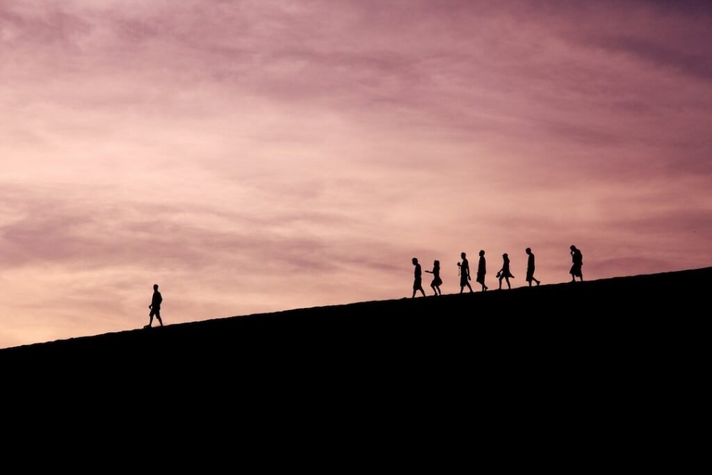 A group of people on a team with one of them way out front coming down a hill.  