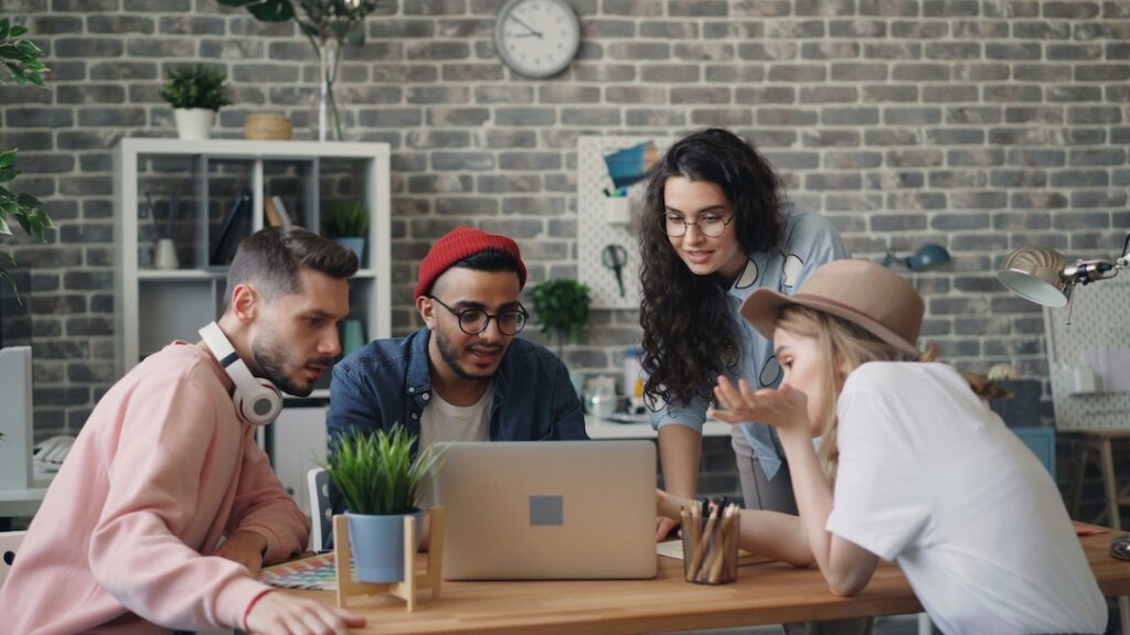 Generation Z employees working together at a desk with a laptop in an office.