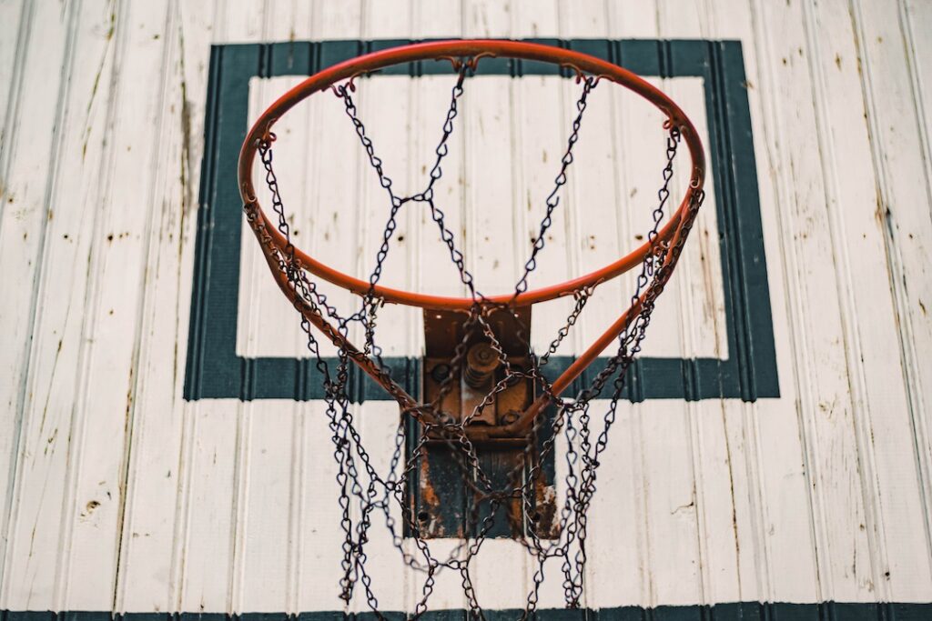 An old basketball hoop on a white backboard with a chain net.