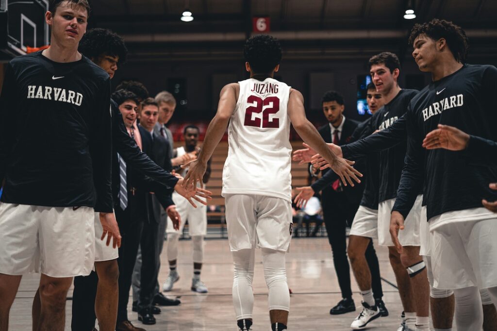 A basketball player running off the bench through the team as his name is announced in the starting lineup.