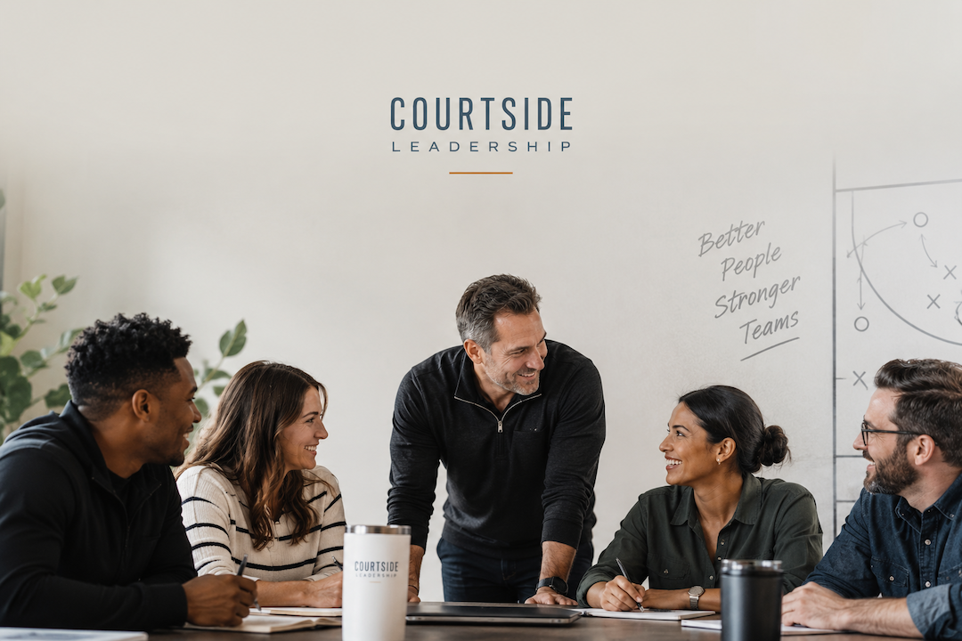 Leader at a conference table with his team and everyone is smiling and engaged.